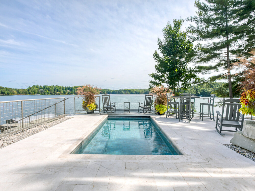 A hot tub set into the stone terrace at the water's edge at Lakemore, looking out over Arbutus Lake.